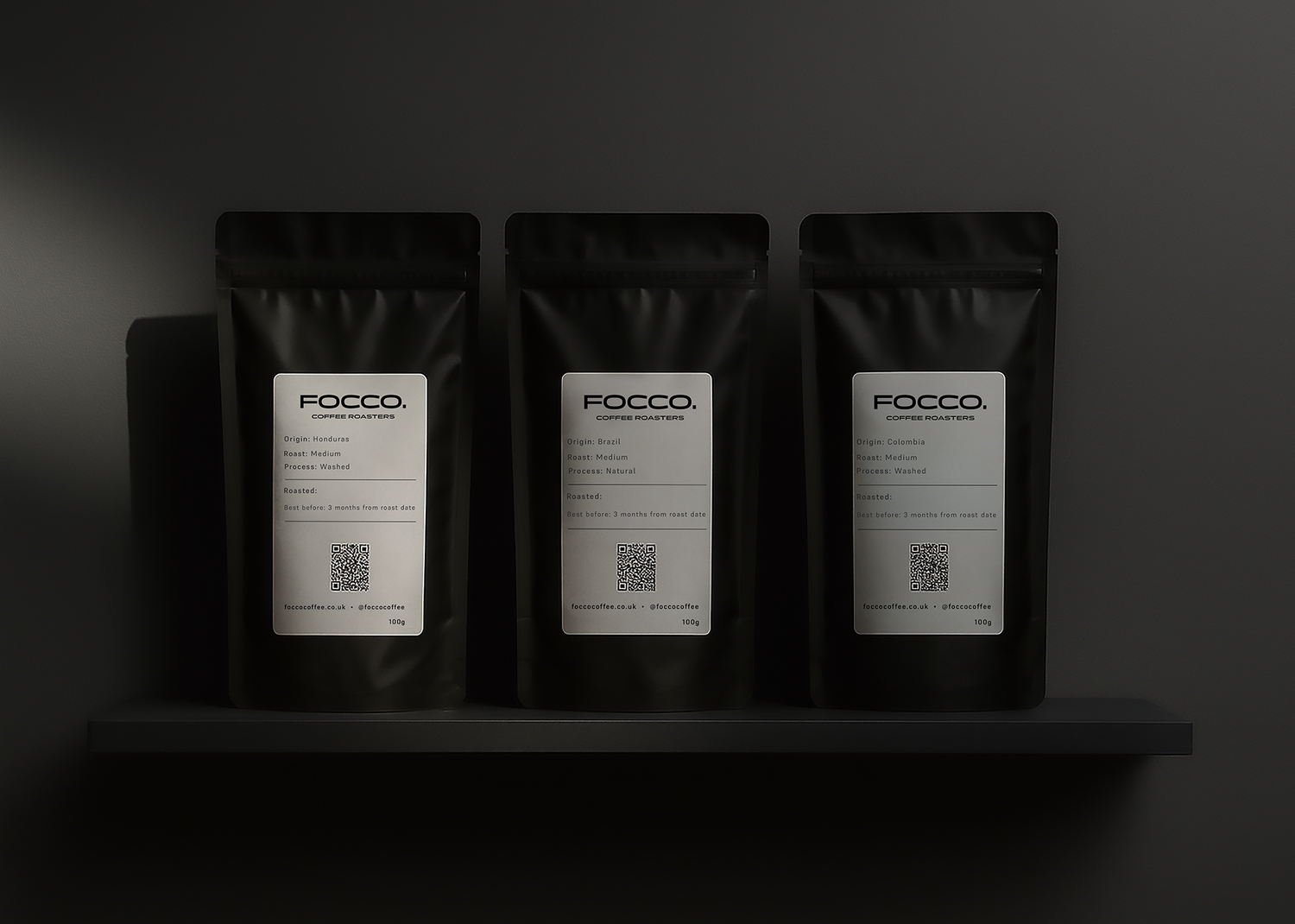 three black coffee FOCCO bags on a shelve with dark background