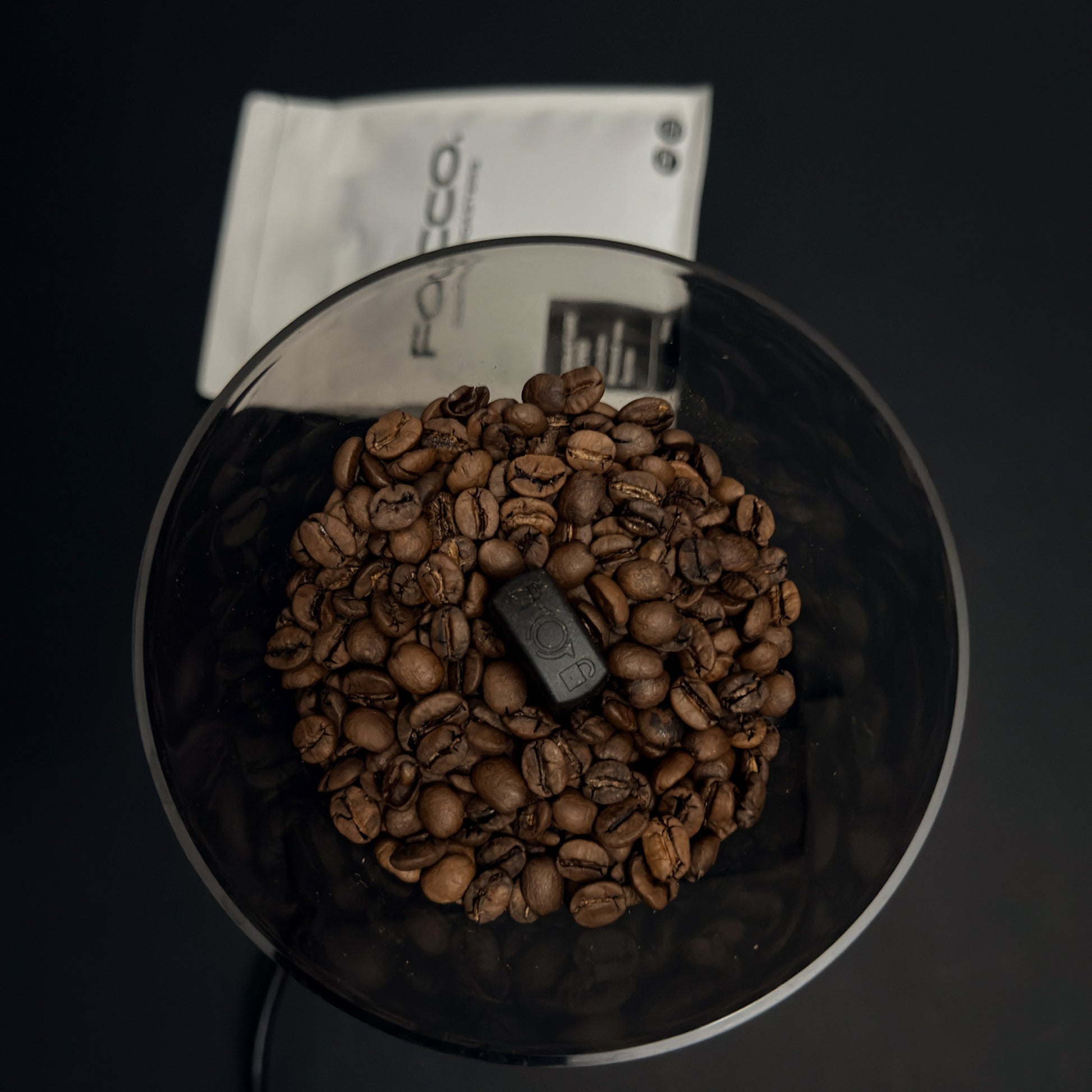 Coffee grinder with coffee beans and a visible brand logo on a dark background