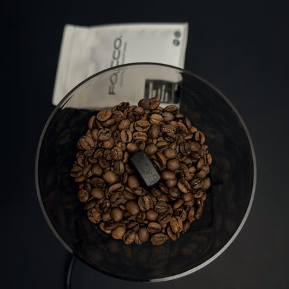 Coffee grinder with coffee beans and a visible brand logo on a dark background