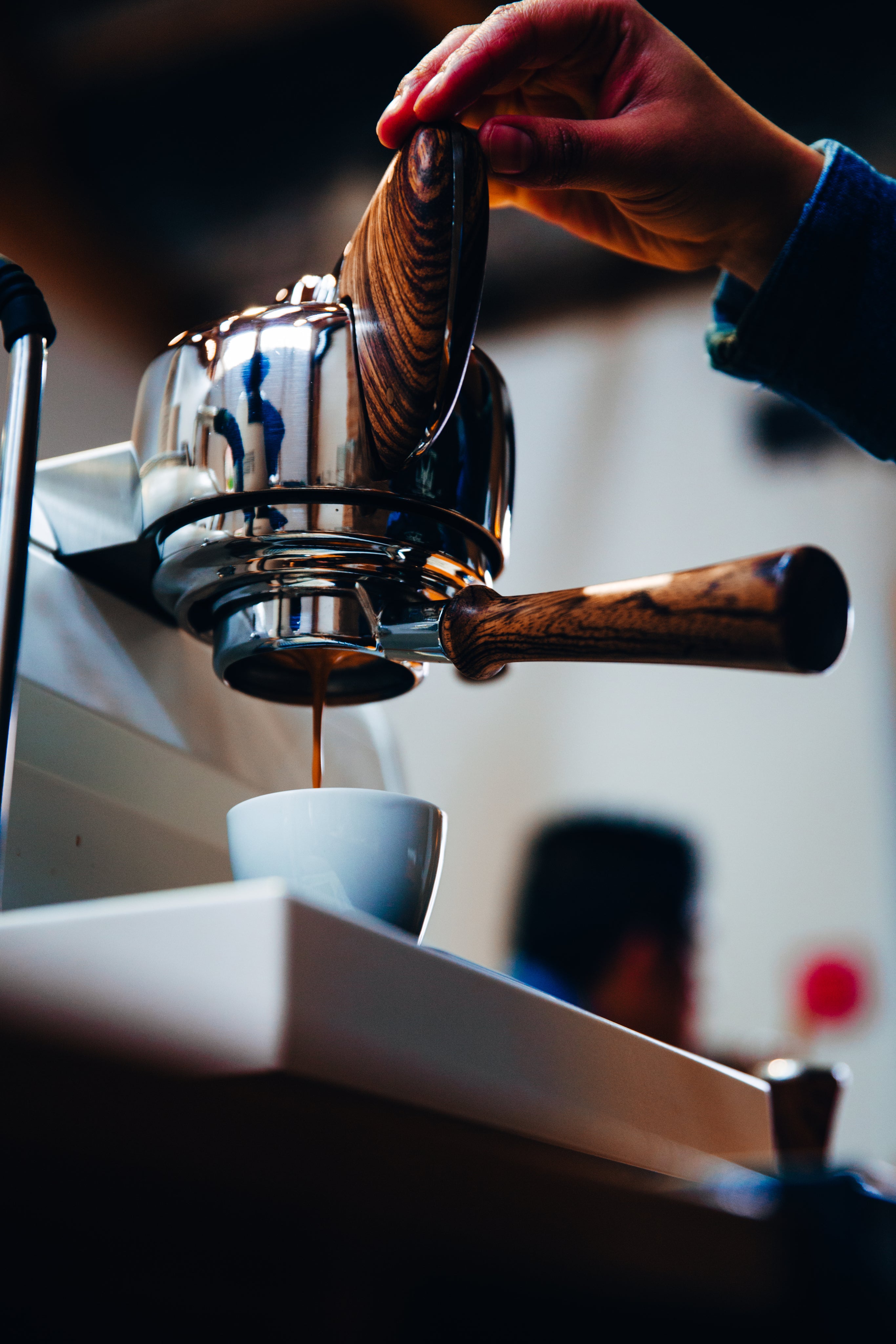 Hand preparing an espresso coffee with dark wood handle