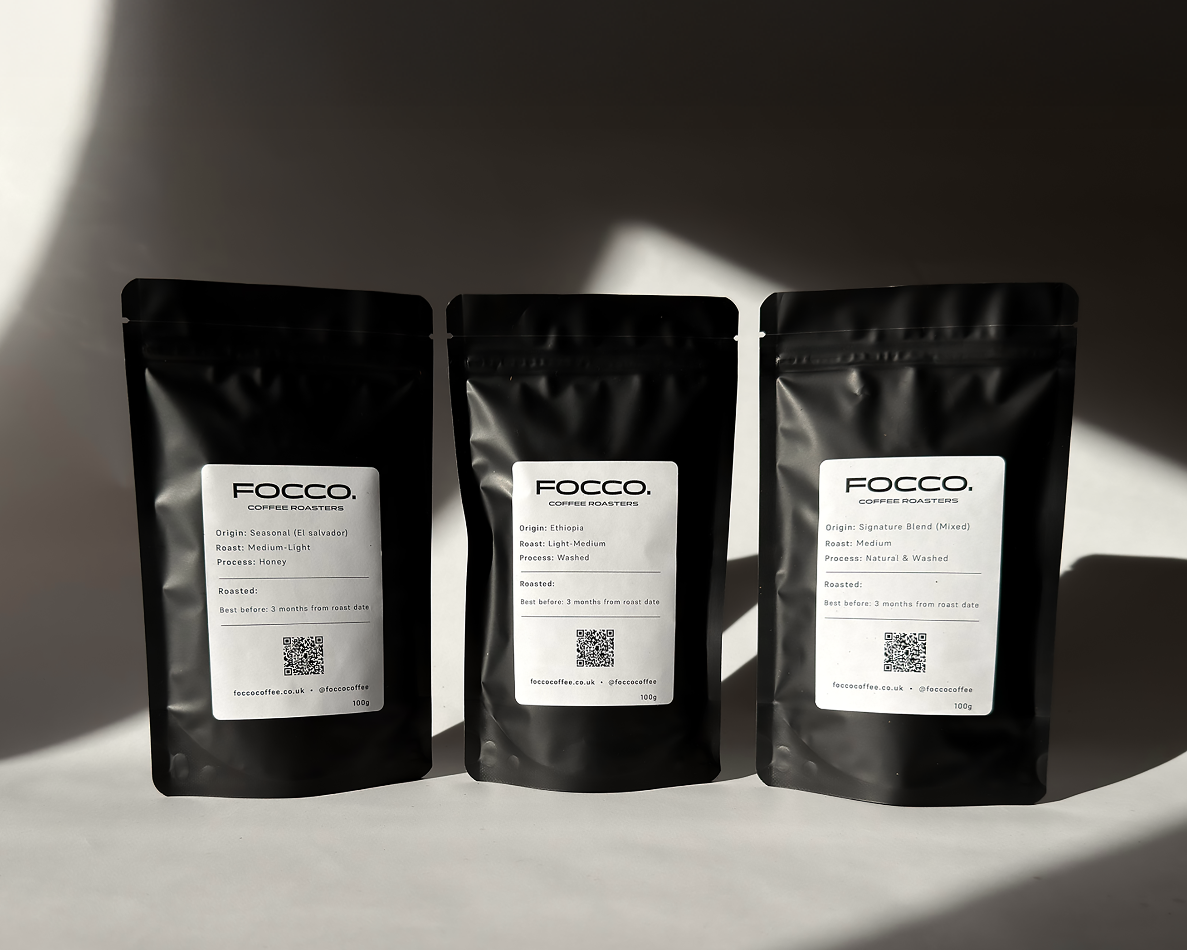 Three black coffee bags with 'FOCCO' branding on a light surface with shadows.