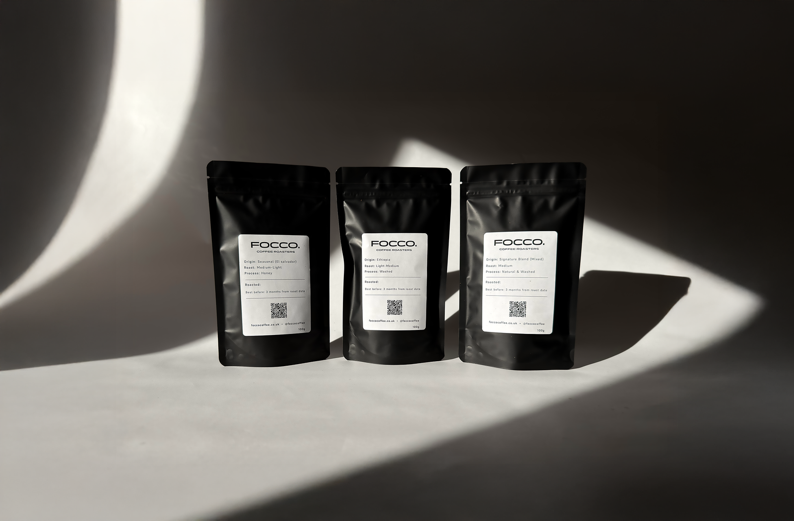 three bags of FOCCO coffee on a shelve with black background.